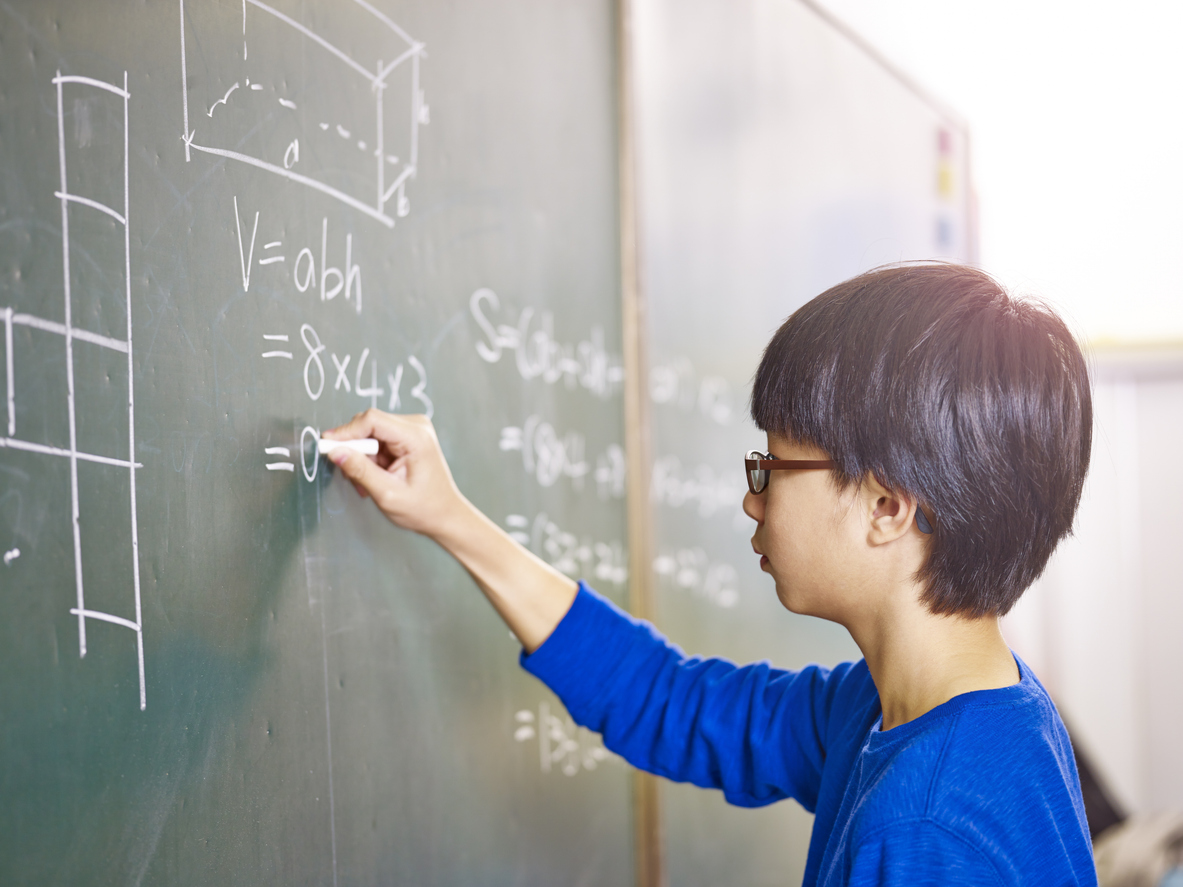 Asian schoolboy solving geometry problem on blackboard
